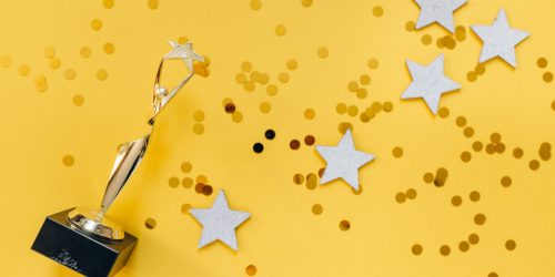 Golden Statuette and Stars on Yellow Background